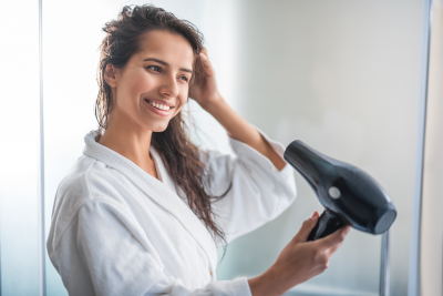 A woman is drying her hair with hair dryer